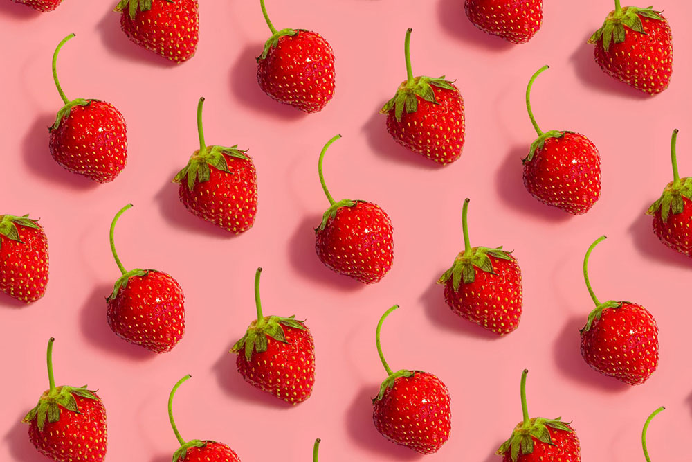 Lot de fraises séparées les unes des autres sur un plan de travail rose saumon. Image de jeremy-bezanger-0QgbyZdhX7k-unsplash